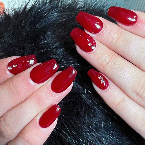Hand with long, glossy acrylic nails painted in bright blue.