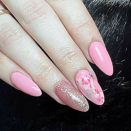 Hands with long, glossy pale pink acrylic nails, two adorned with small rhinestones, and a silver ring with a large gemstone.