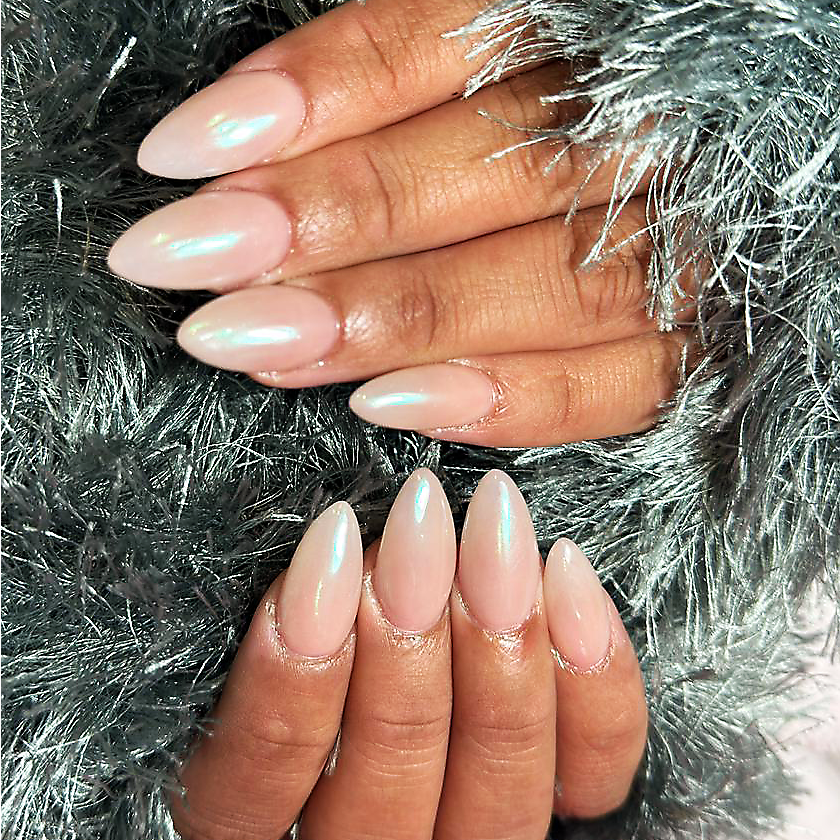Hands with long almond-shaped nails painted in a pearlescent pale pink shade, resting on a silver furry fabric.